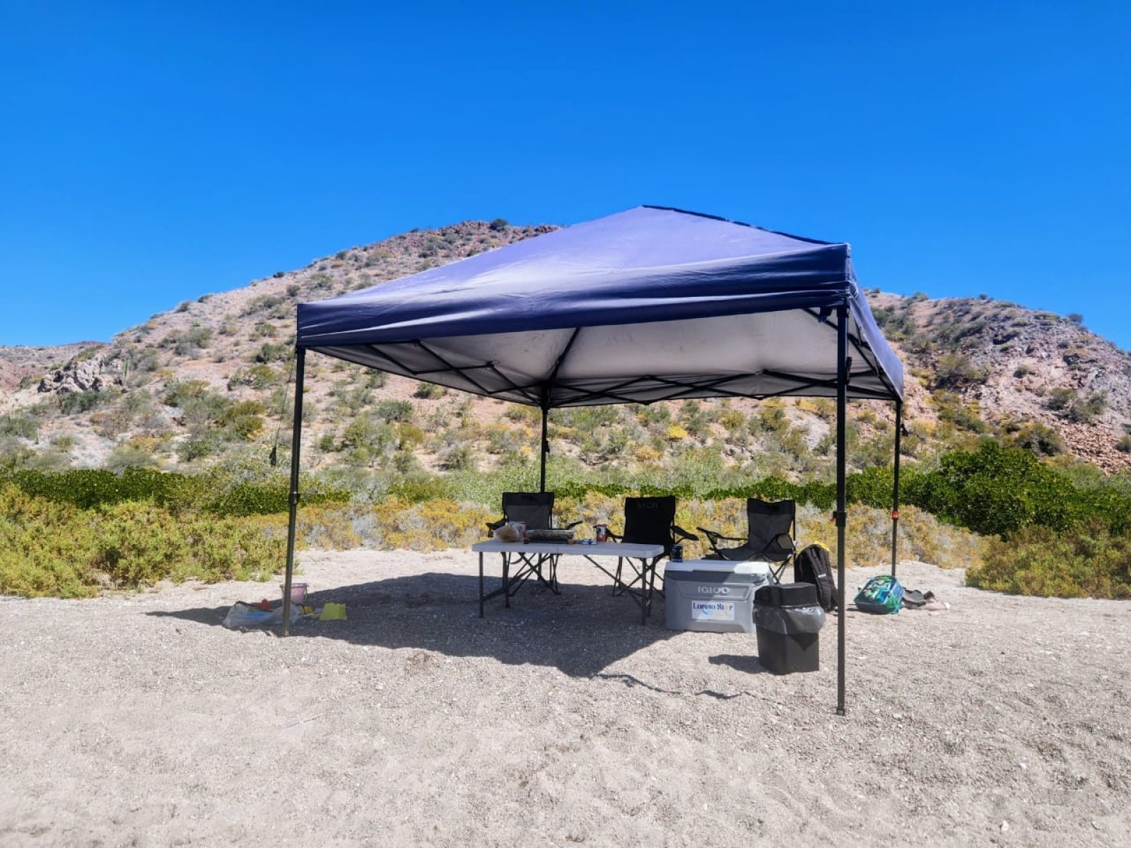 Nuestra carpa de sombra, sillas e hielera montadas en una playa de isla en Loreto